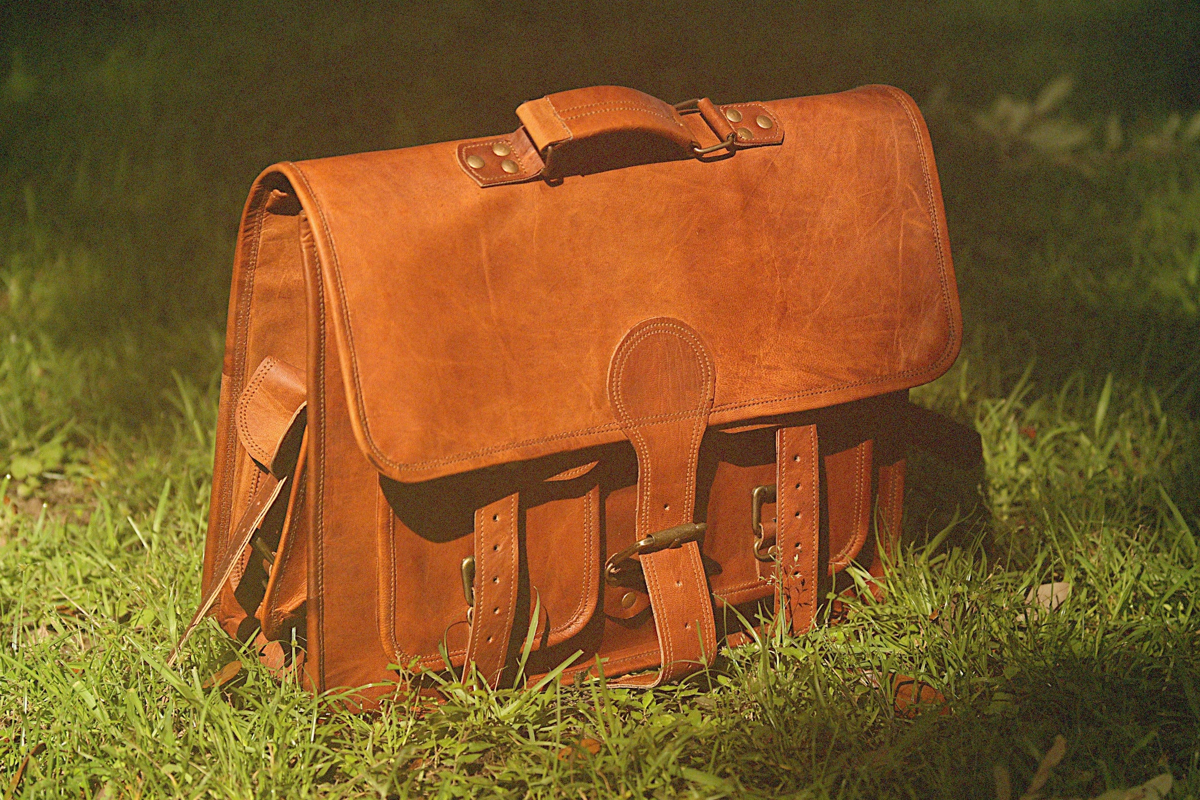 Brown leather satchel on grass